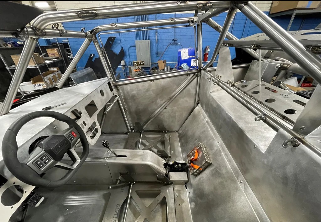Raw aluminum cockpit interior with steering wheel on a Polaris Turbo R race chassis